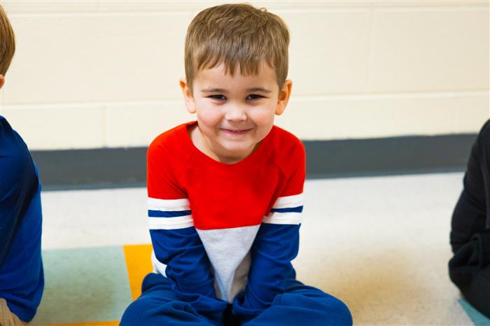 young male student sitting on the floor smiling